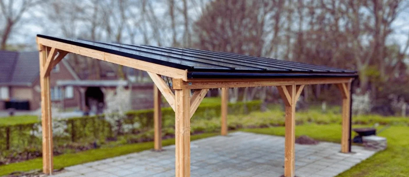 Close-up van een houten carport met dak van zonnepanelen in een tuin, onscherpe achtergrond van een woonwijk.