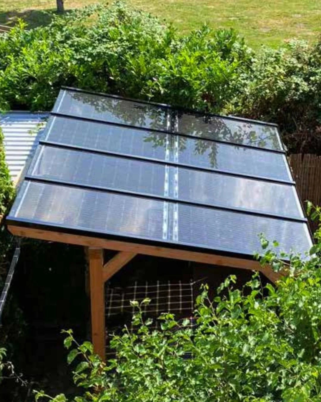 Houten overkapping met zonnepanelenin tuin omringt door planten