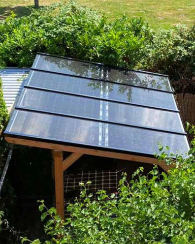 Houten overkapping met zonnepanelenin tuin omringt door planten